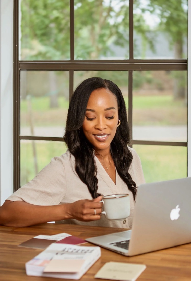 Megan Noel working at her desk with a laptop and a mug